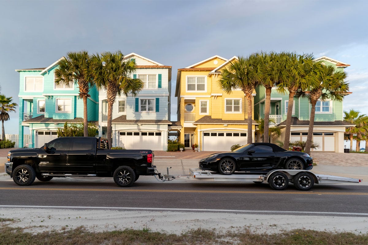 Side View Of Black Truck Hauling Black Car On Polaris Open Car Hauler